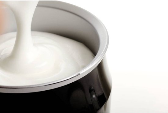 Zwarte melkopschuimer met een romige, opgeschuimde melk die uit de rand stroomt.