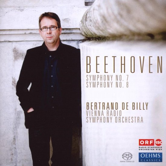 Homme en costume noir devant la pochette du CD de Beethoven.