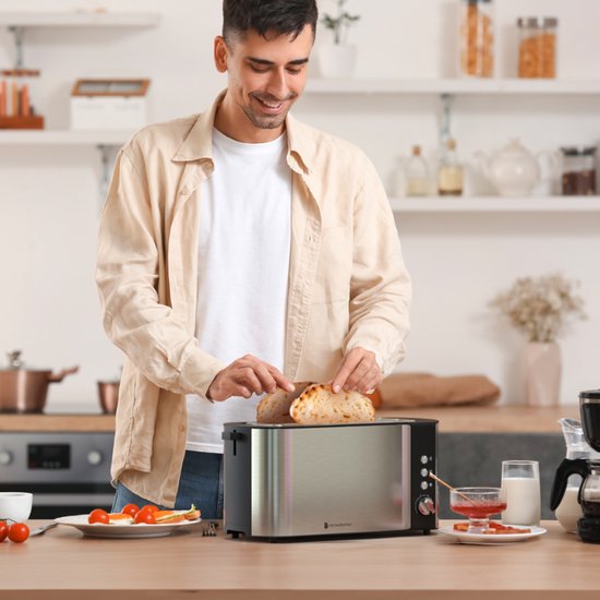 Homme plaçant des toasts dans un grille-pain inox à 2 longues fentes.
