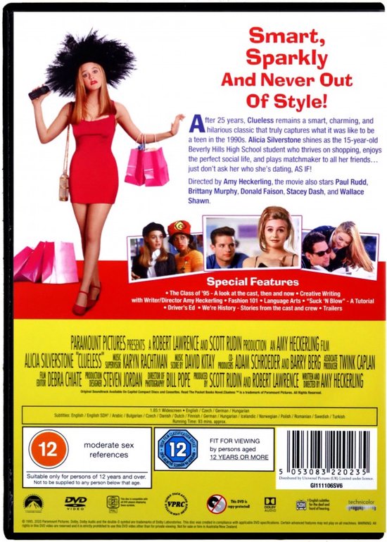 Alicia Silverstone in rode jurk, zwarte hoed, hoge hakken en met handtassen.