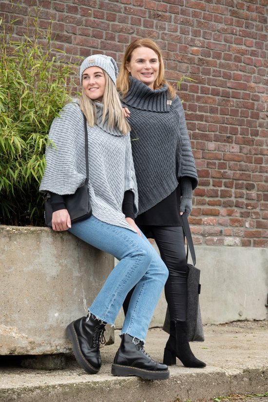 Twee vrouwen in gebreide ponchos, waarvan één een grijze met col, de ander grijs met vleermuismouwen.