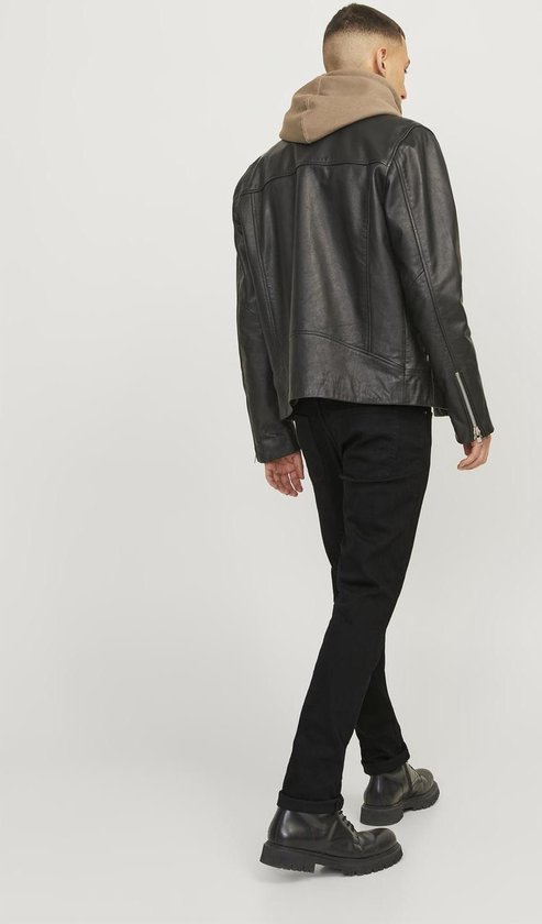 Model loopt weg in zwarte jeans, een bruine hoodie en een zwarte leren jas.