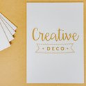 Witte A3 kaart met gouden tekst "Creative DECO" en een lint-icoon.