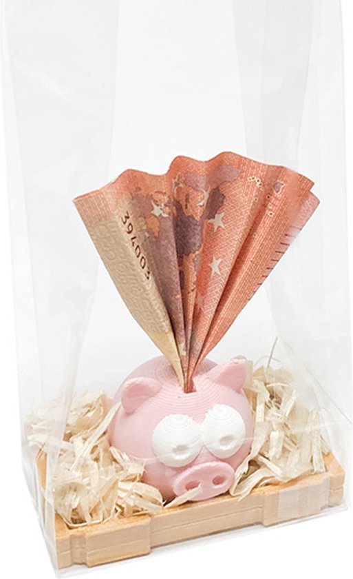 Roze spaarvarken met grote witte ogen en een papieren eurobiljet uit de spaar gleuf, staand in houtsnippers.