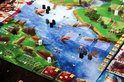 Overzicht van het bordspel "Rovers van de Noordzee" met gebouwen, schepen en dobbelstenen.