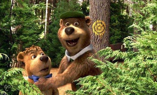 Yogi Bear en Boo Boo tussen de bomen in een bos, met een groene baret op.