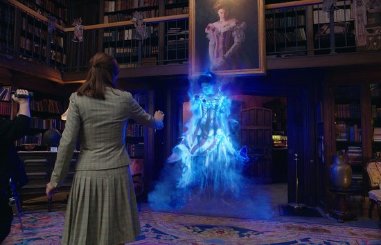 Vrouw in geruit pak kijkt naar een blauwe, gloeiende geest in een kamer met boekenkasten.