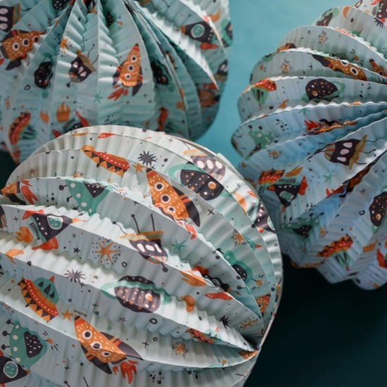 Drie lichtblauwe papieren lampionnen, deels geopend, met ruimtevaartprint van raketten en UFO's.