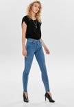 Model in lichte spijkerbroek en zwarte top met luipaardprint, van voren gezien.