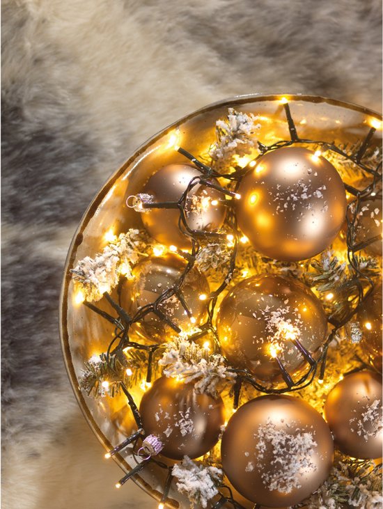 Een schaal gevuld met koperkleurige kerstballen, dennentakjes en warm witte LED-lampjes.