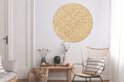 Décoration murale ronde imprimé rotin dans un salon à côté d'un banc et d'un fauteuil en bois.