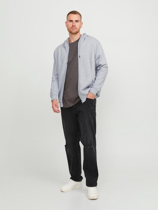Man met grijze hoodie, donker T-shirt en zwarte jeans.