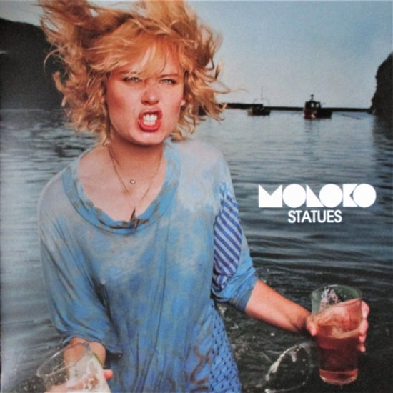 Vrouw met blond haar, blauw shirt, met twee glazen bier in de hand, met 'MOLOKO STATUES' tekst.