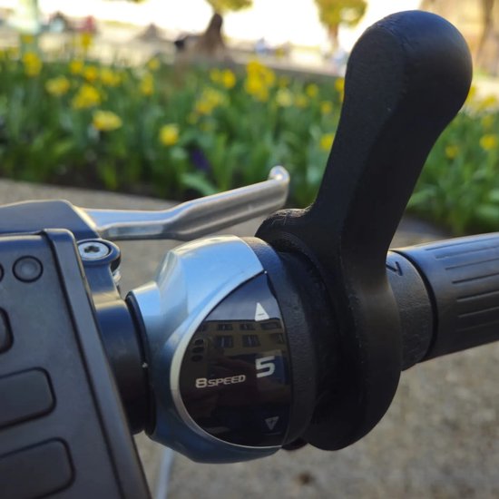 Zwarte ergonomische schakelhulp op een fietsstuur, met "8SPEED" aanduiding.