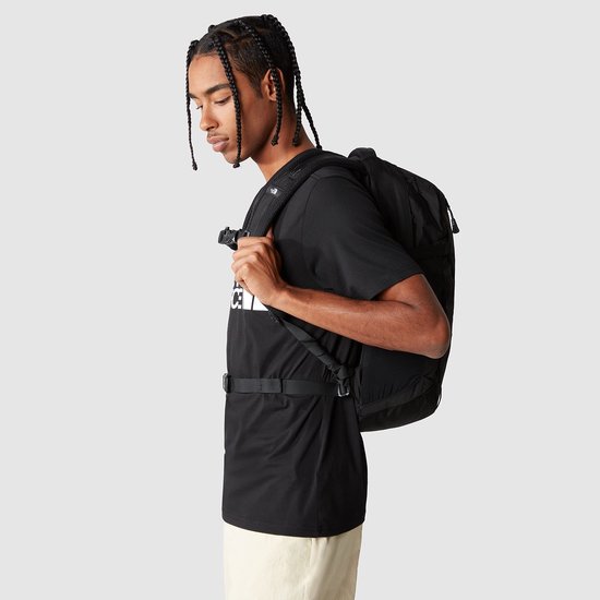 Man met een zwarte The North Face rugzak, van opzij gezien.