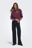 Model draagt een paarse sweater met kanten accenten op de mouwen, gecombineerd met donkerblauwe wijde jeans.