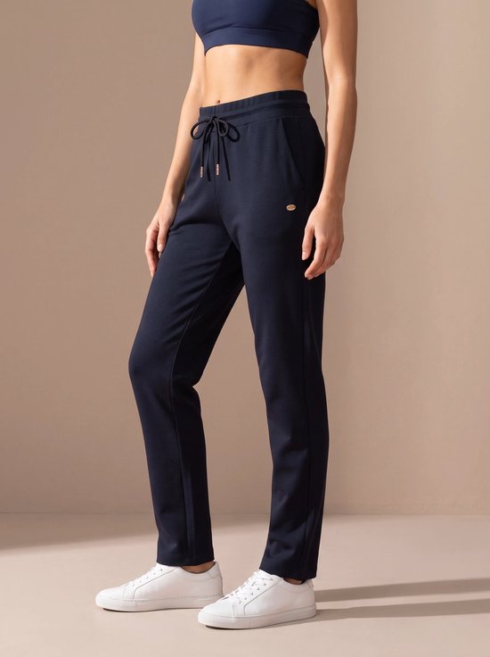 Donkerblauwe sportbroek met trekkoord in de taille, gedragen door een model met witte sneakers.