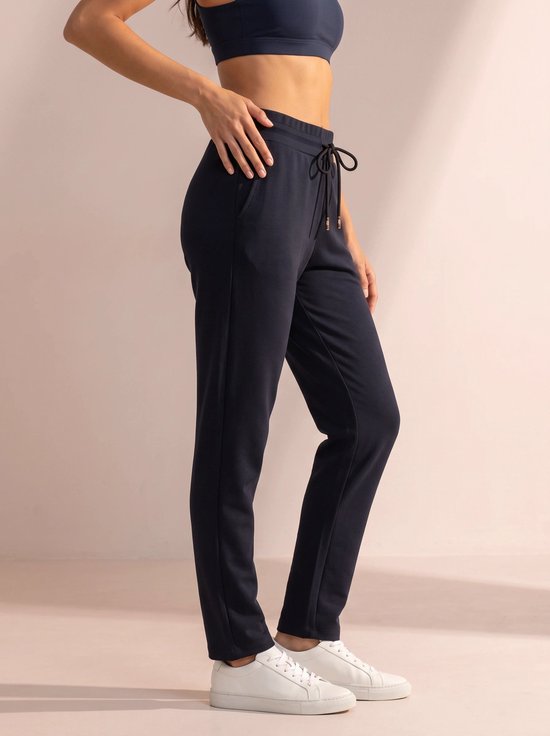 Donkerblauwe sportbroek met trekkoord in de taille, gedragen door een model met witte sneakers.