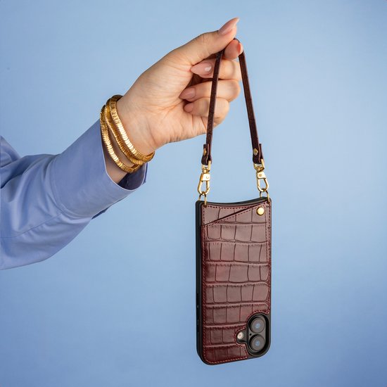 Bourgondische croco backcover voor Samsung S25 Ultra aan een goudkleurige ketting, vastgehouden bij een lichtblauw hemd.