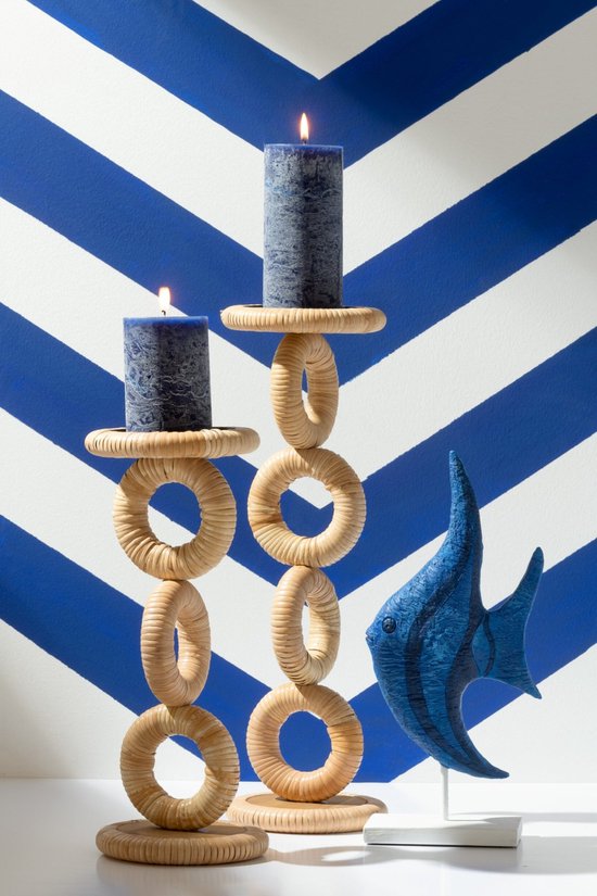 Gevlochten kandelaar van naturel gekleurd hout met twee blauwe kaarsen, naast een blauwe visdecoratie.