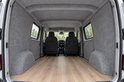 Binnenkant van een bestelwagen bekleed met grijze viltpanelen en een houten vloer.