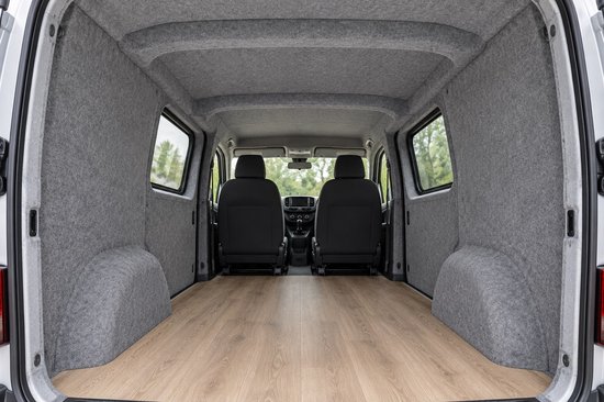 Binnenkant van een bestelwagen bekleed met grijze viltpanelen en een houten vloer.