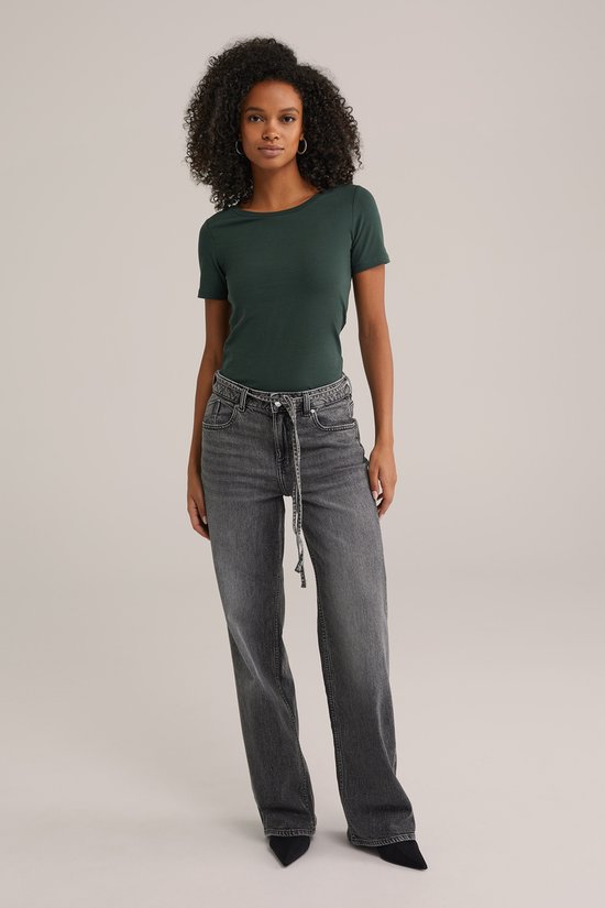 Model met donkergroen t-shirt met korte mouwen en grijze jeans met ceintuur.