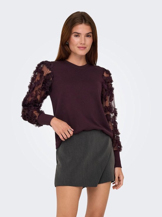 Model in een wijnrode trui met lange mesh mouwen met bloemapplicaties.