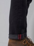 Donkergrijze jeans met omgeslagen pijpen met rode accenten en bruine schoenen.