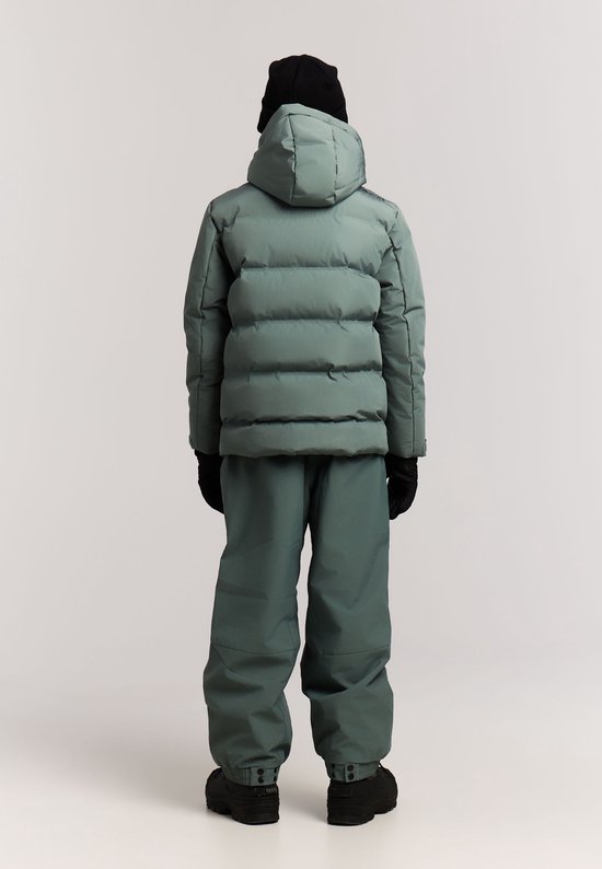 Jongen in grijze ski-uitrusting: winterjas, skibroek, zwarte muts en handschoenen. Achteraanzicht.