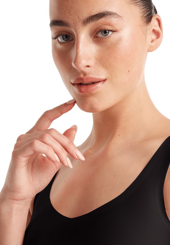 Close-up van een vrouw die een zwart singlet draagt, met de hand op de kin.