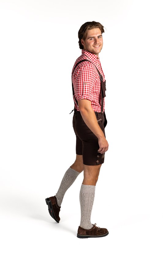 Man naar links gedraaid, draagt rood-wit geblokt overhemd, bruine lederhosen met bretels, grijze sokken en bruine schoenen.