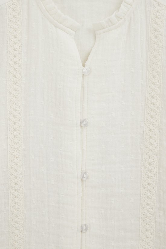Off-white blouse met knoopjes, rucheskraag en ingeweven stippen.