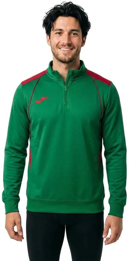 Groene Joma Championship VII sweater met halve rits, rode schouderdetails en rood logo op de borst, gedragen door man.