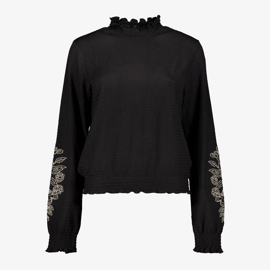 Zwarte blouse met rucheskraag, ruche boorden en geborduurde bloemen op de mouwen.