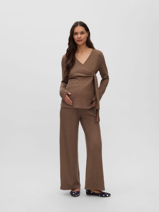 Zwangere vrouw in een bruine, fijngebreide outfit met wikkel-top en bijpassende broek met wijde pijpen.