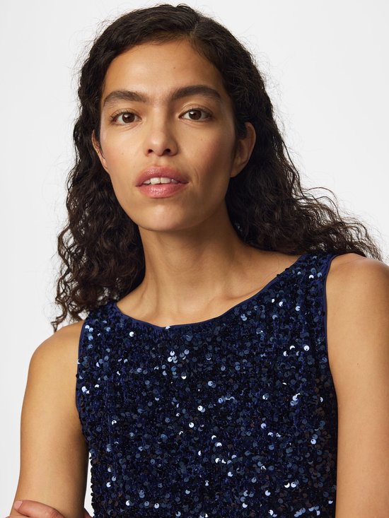 Close-up van het décolleté van een vrouw in een donkerblauw mouwloos topje met pailletten.