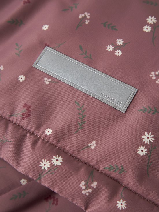 Detail van roze jas met bloemenprint en reflecterend label.