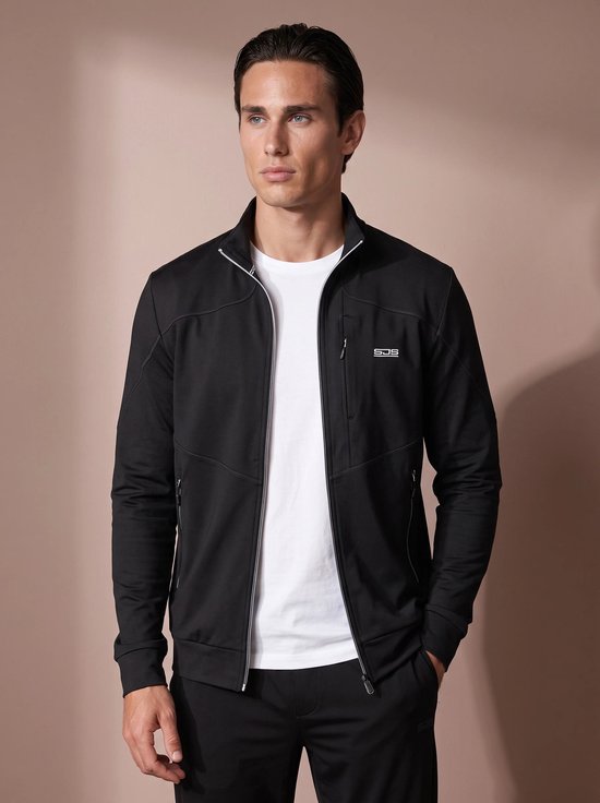 Model draagt een zwart sportvest met opstaande kraag, witte rits en SJS-logo op de linkerborst.