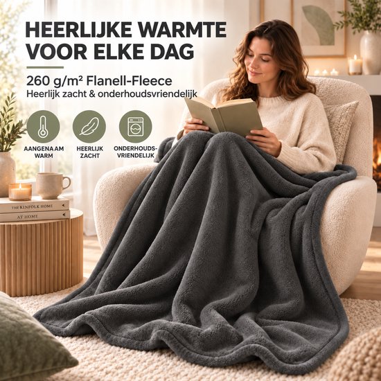 Vrouw leest in een fauteuil onder een antracietgrijze 260 g/m² flanel-fleece plaid, zacht en onderhoudsvriendelijk.