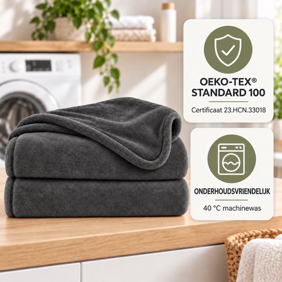 Antracietgrijze fleece deken op een houten aanrecht, met labels voor Oeko-Tex Standard 100 certificering en 40°C machinewas.