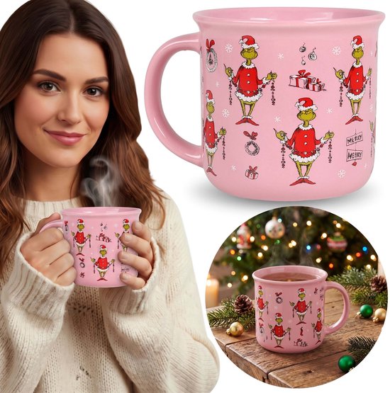 Roze Grinch-kerstmok met oor, vastgehouden door een vrouw in witte trui, met patronen van de Grinch in kerstoutfit.