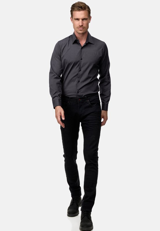 Model draagt een donkergrijs Rusty Neal overhemd, zwarte slim fit jeans en zwarte laarzen.