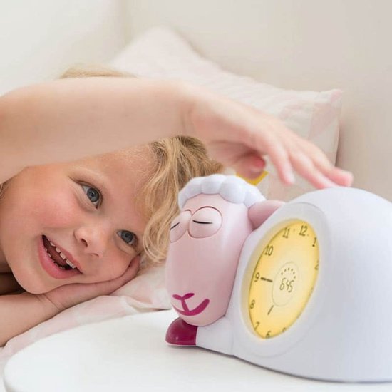 Lachend kind raakt roze schaap wekker aan met gele verlichting.