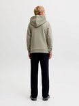 Jongen met blonde haren draagt een olijfgroene hoodie en zwarte joggingbroek. Zijaanzicht achter.