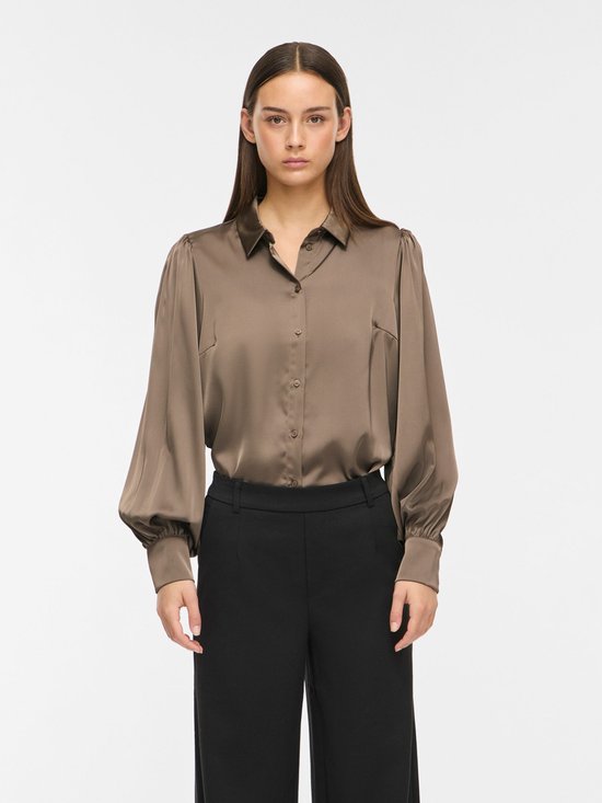 Taupe satijnen blouse met pofmouwen en knoopjes, gedragen door een model.