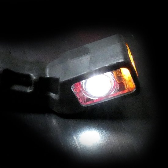 Zwarte LED-markeringslamp met een helder wit licht en een oranje zijlamp in het donker.