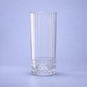 Transparant longdrinkglas met verticale ribbels en een gedetailleerd diamantpatroon aan de onderkant, op een paarse achtergrond.