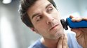 Un homme se rase le visage avec un rasoir Philips Série 5000 bleu.