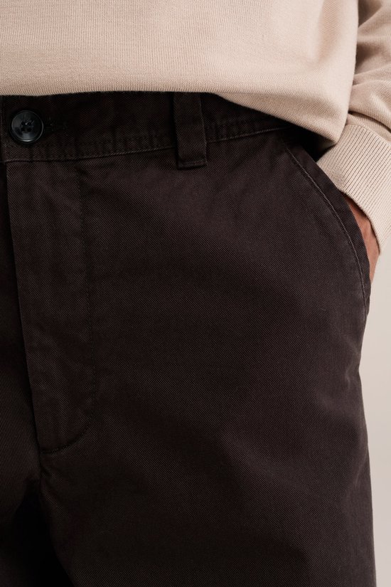 Detailopname van de bruine chino met knoop en riemlussen.